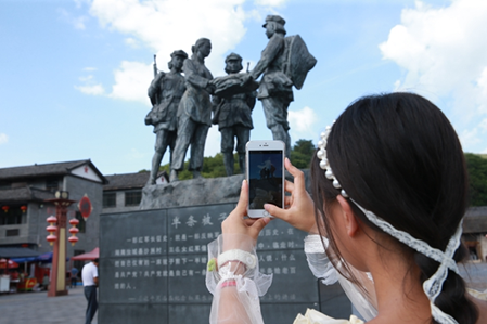 游客朱志群在村里游玩，不忘用手机记录行程